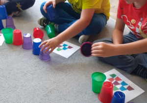 Antoś i Kamil uważnie odwzorowują wzór z kolorowych kubków