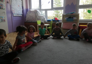Dzieci siedzą na dywanie i przesyłają sobie iskirekę życzliwości