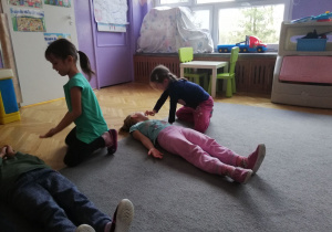 Ala i Gabrysia uczą się udzielać pomocy dzieciom, które leżą na dywanie