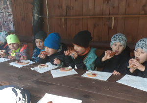 Dzieci z apetytem zajadają pieczoną kiełbaskę
