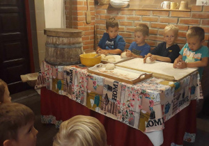 Mikołaj, Wiktor, Marcel pracują przy produkcji chlebka