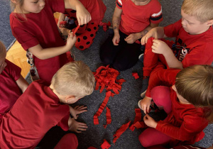 Dzieci przgotowują czerwoną krepinę do pracy